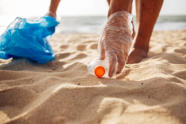 Woman picking up trash from the beach